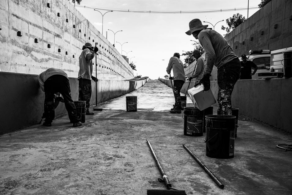 Group of men cleaning a concrete walkway in Londrina, Brazil.