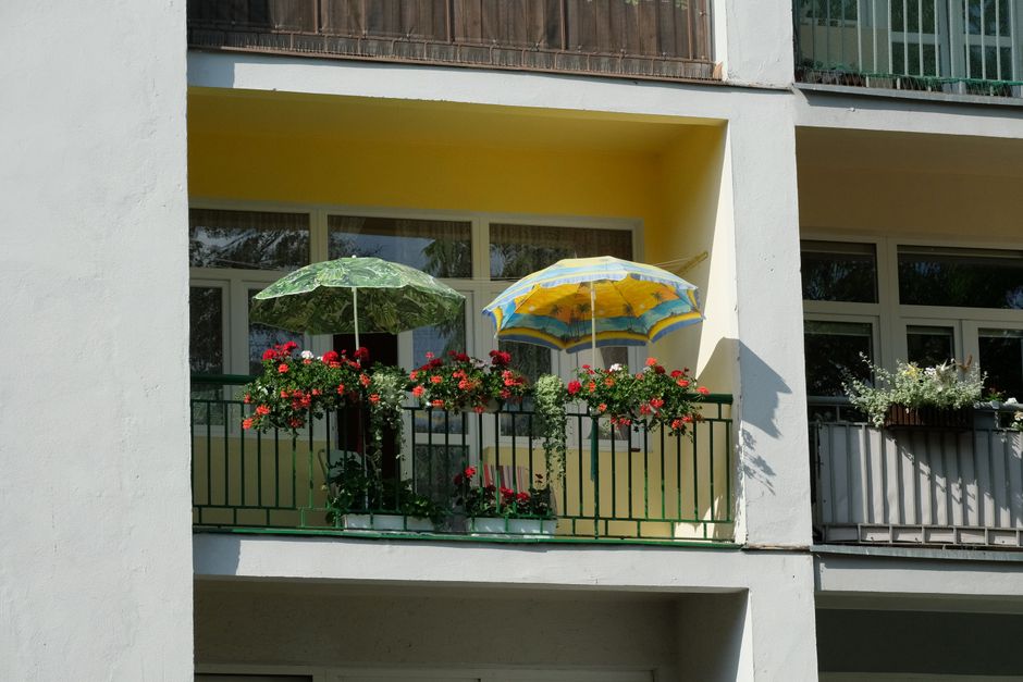 A cozy balcony with vibrant flowers and colorful umbrellas in a residential setting.